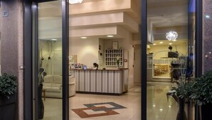 A reception area with a counter, seating, and a decorative floor pattern. - Hotel Primavera (Stresa)