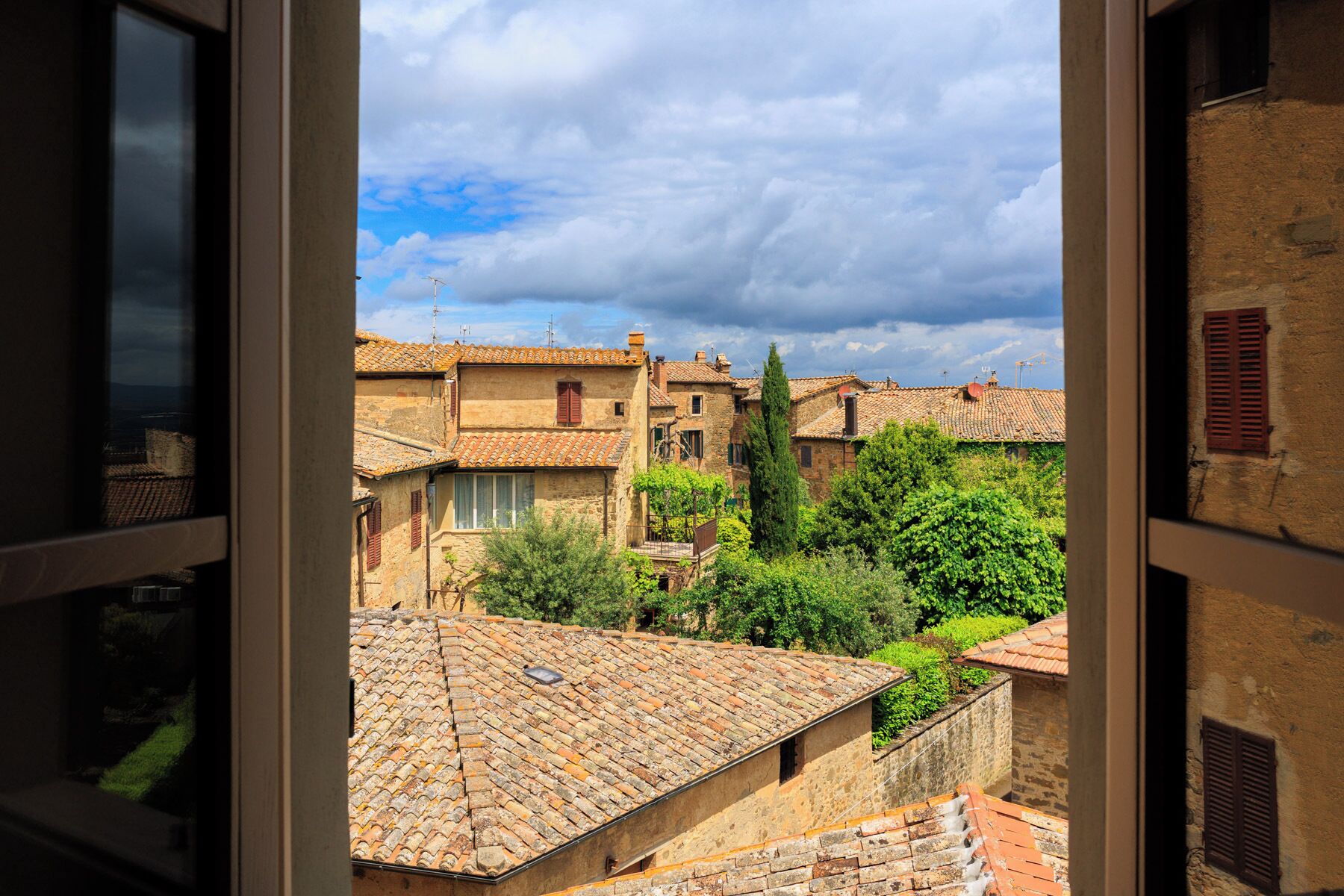 A view of traditional stone buildings with terracotta roofs, visible through an open window.