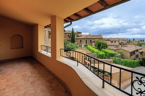 A balcony with a view of traditional buildings and a stone wall.
