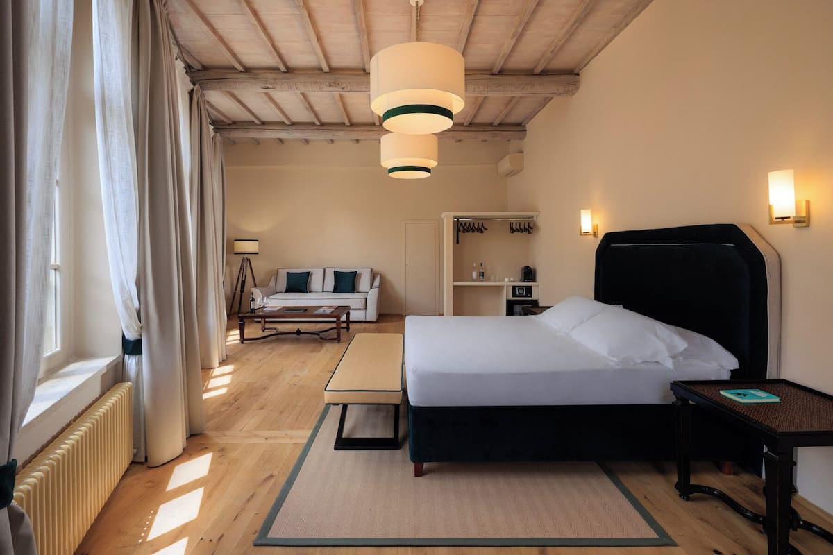 Ein Hotelzimmer mit Bett, Nachttisch, Lampe und Blick ins Freie.