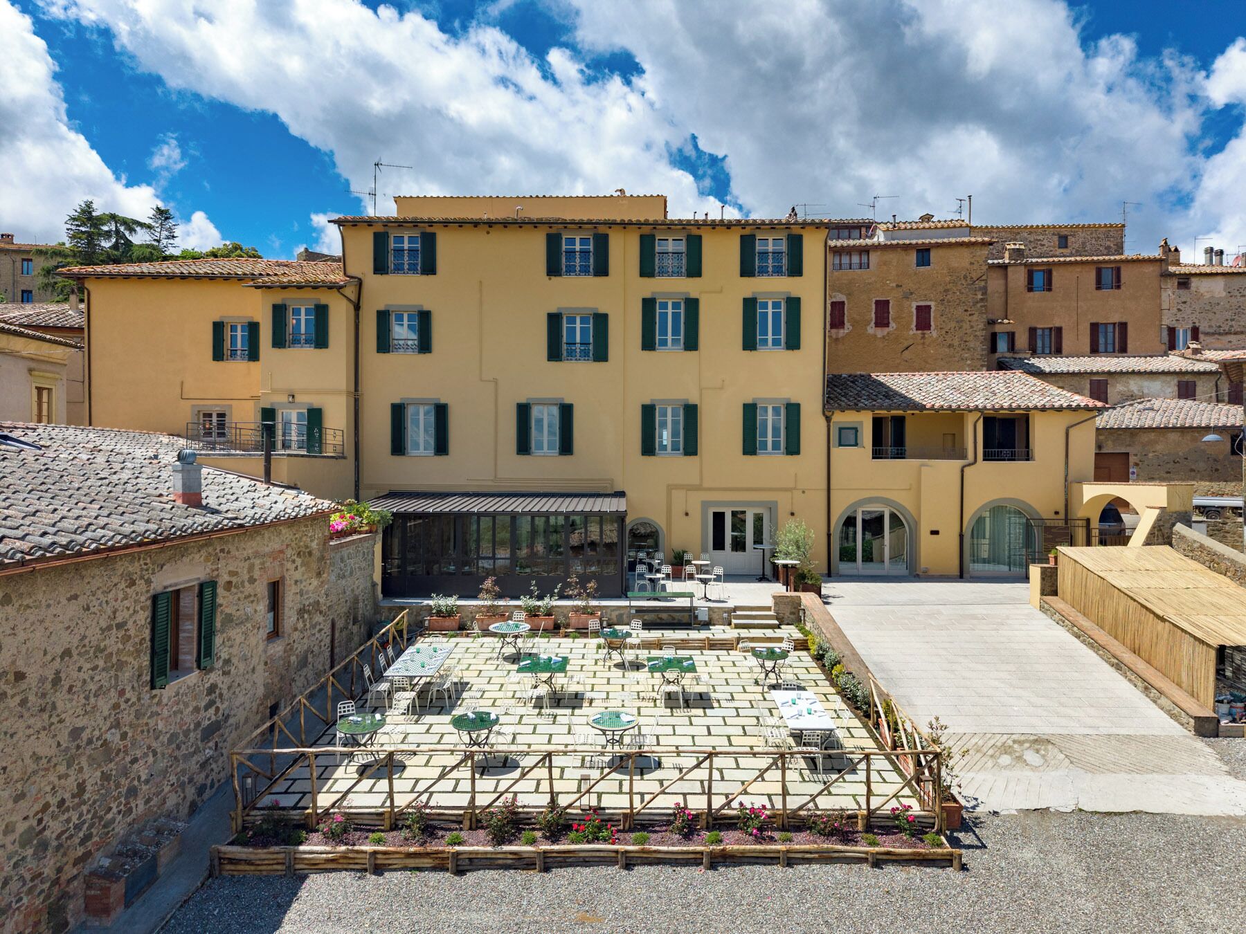 Un cortile con posti a sedere all'aperto, un edificio con diverse finestre e un muro in pietra.