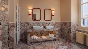A bathroom with marble floors, two sinks, a towel rack, and a window.