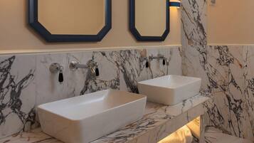 A bathroom with two white sinks, marble walls, and a towel rack.