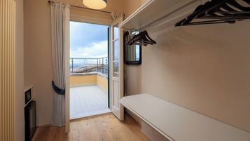 Een balkon met uitzicht, een bankje, een hangende kapstok en een deur die naar het balkon leidt.