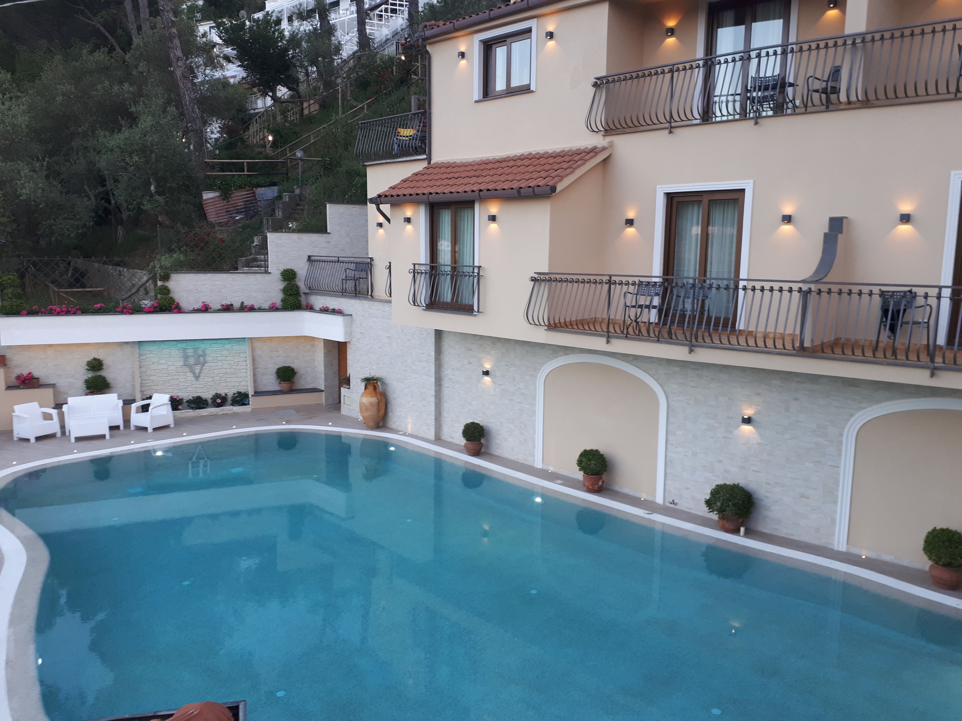 A poolside area with a swimming pool, outdoor seating, and a building with balconies.