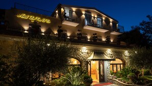 A hotel with a stone facade, balconies with metal railings, and a well-lit entrance. - La Vue D'Or (Sorrento)