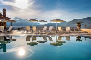 Una piscina al aire libre, sombrillas, sillones reclinables de piscina