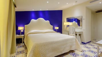 A hotel room with a large bed, a bedside table, a mirror, and a bathroom area.