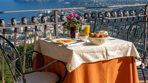 A table set on a terrace with a city and sea view. - La Vue D'Or (Sorrento)