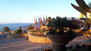 A landscaped area with a large planter, a stone wall, and a view of the sea. - La Vue D'Or (Sorrento)