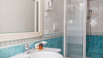 Un baño con lavamanos, inodoro y ducha blancos.