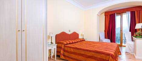 Une chambre d’hôtel avec un grand lit, un bureau avec une lampe, une chaise et une vue sur l’extérieur.