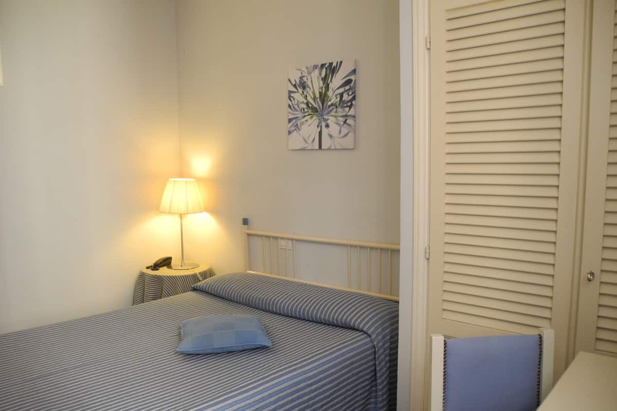 A bedroom with a bed, bedside lamp, and a wall-mounted artwork.