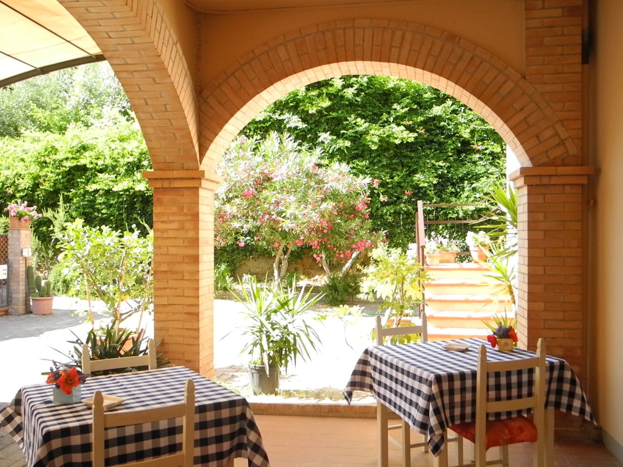 An outdoor patio with two tables and chairs, covered by a checkered tablecloth.