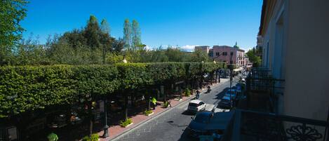 Vista de la calle con árboles, coches aparcados y edificios.