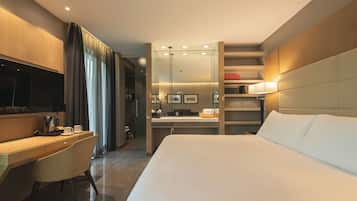 A modern hotel room with a large bed, a desk, a chair, a TV, a bathroom, and a bookshelf.