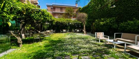 A courtyard with stone paving, outdoor furniture, and a garden area with white flowers.