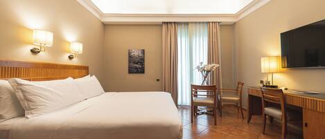 A hotel room with a bed, desk, chair, TV, and lamps.