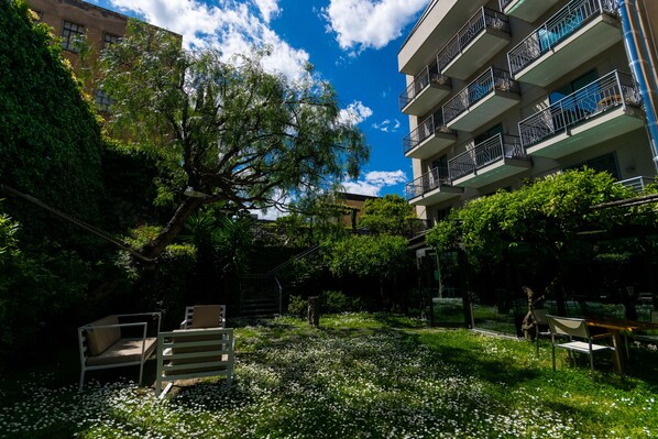 Um pátio com um banco, uma árvore e um edifício com varandas.