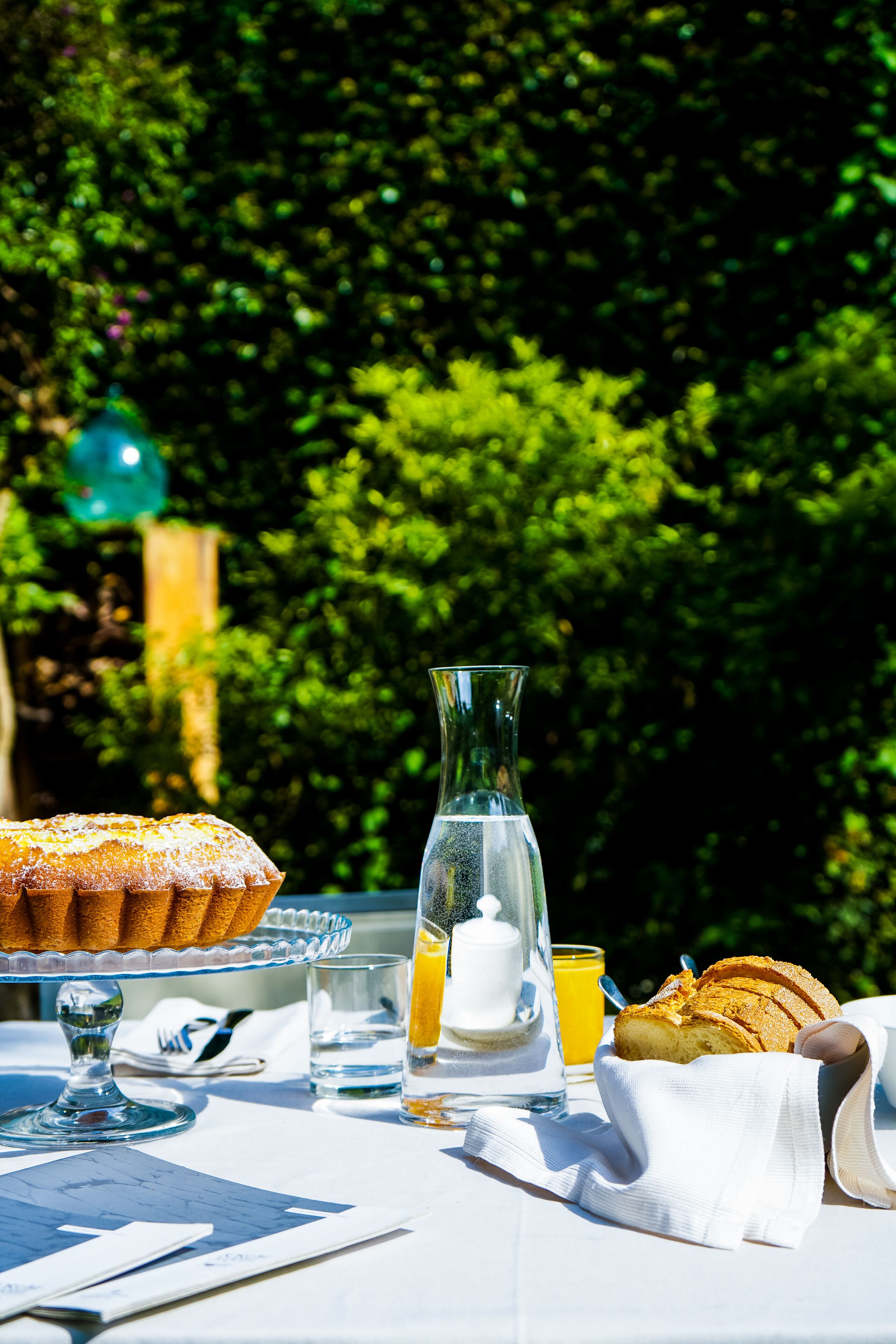 A table with a cake, bread, a pitcher, and glasses of orange juice.