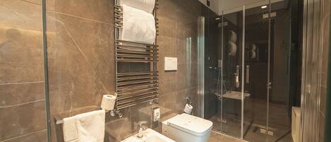 Een moderne badkamer met een douchecabine van glas, een bidet en een handdoekhouder.