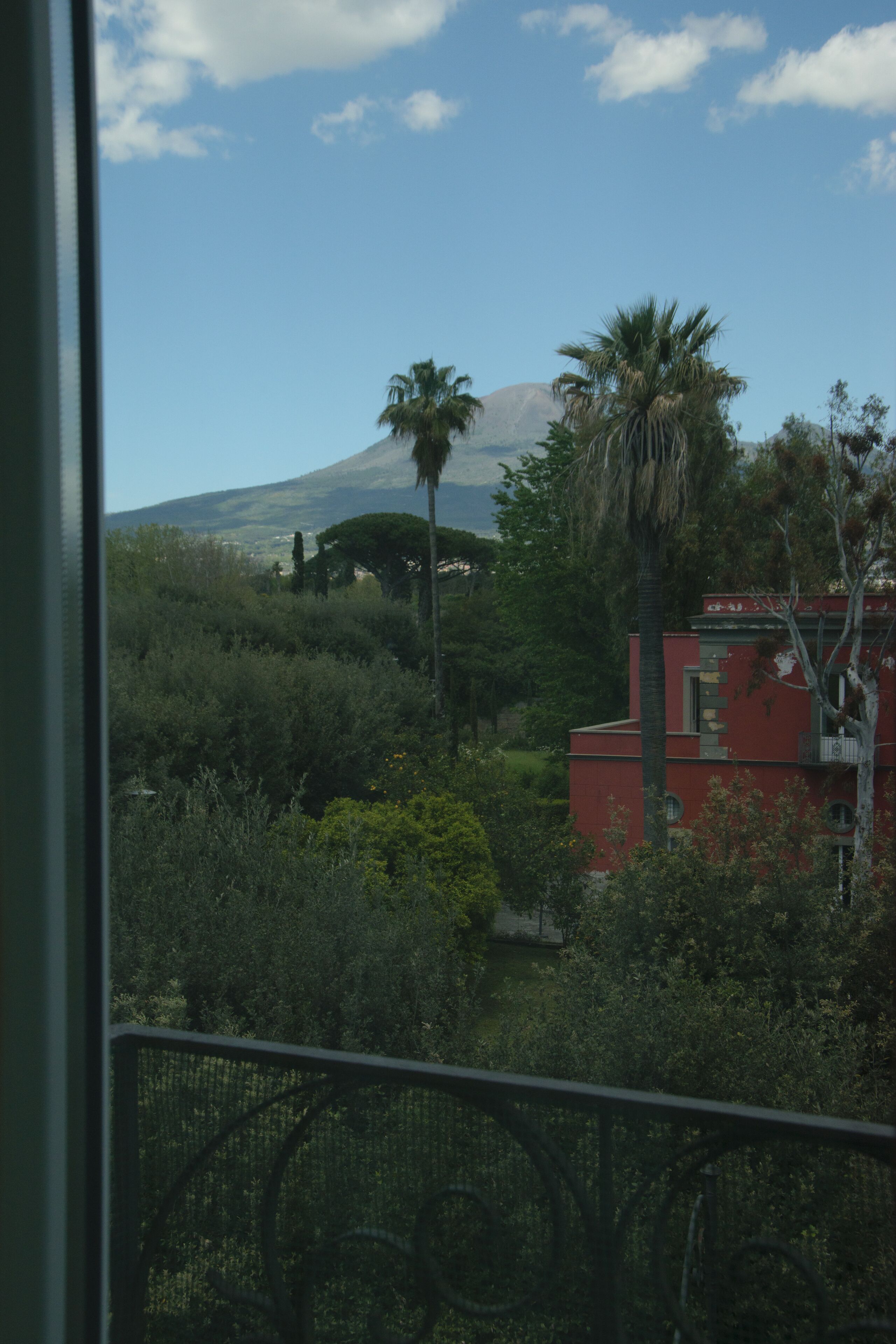 A view of a mountainous landscape with a red building, palm trees, and dense greenery.
