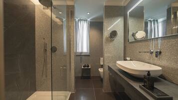 A modern bathroom with a glass-enclosed shower, a large sink, and a mirror.