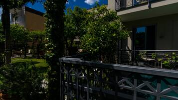 A courtyard with a metal railing, potted plants, and a building with balconies.