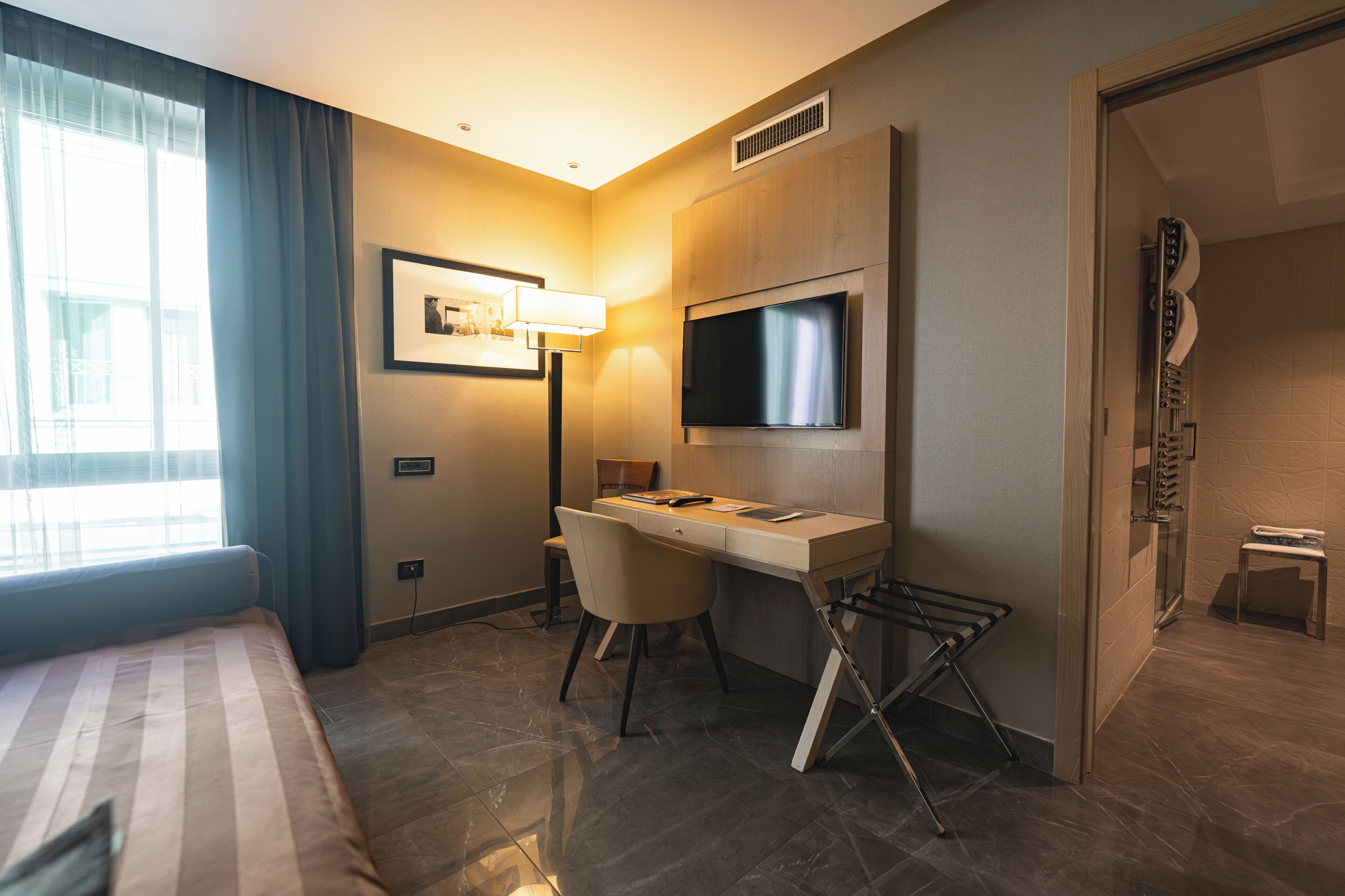Ein Hotelzimmer mit Bett, Schreibtisch, Stuhl, Fernseher und Dusche.
