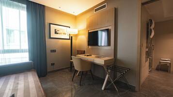 Ein Hotelzimmer mit Bett, Schreibtisch, Stuhl, Fernseher und Dusche.
