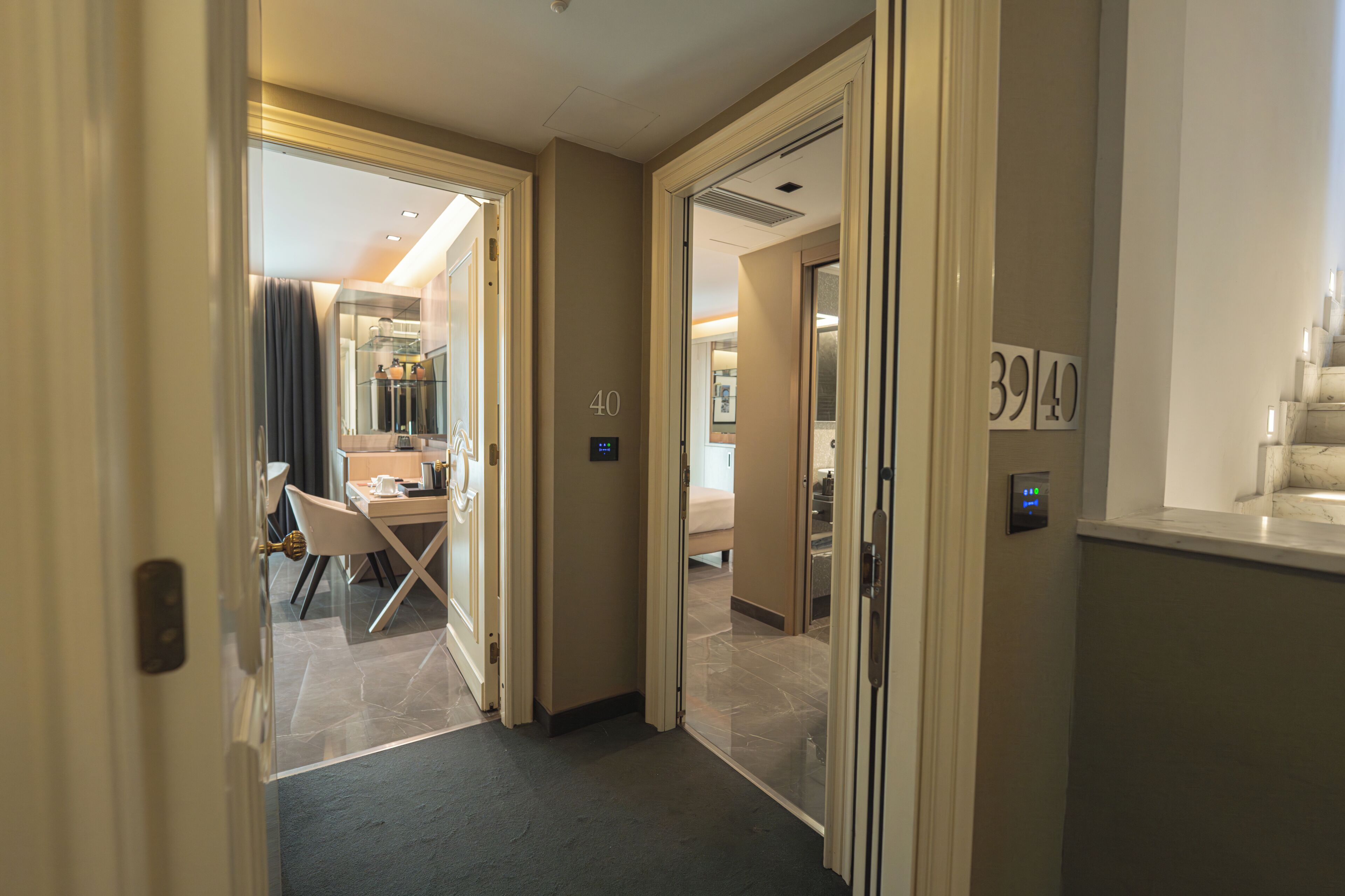 A hotel corridor with a dining area, a bed, and a bathroom.