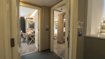 A hotel corridor with a dining area, a bed, and a bathroom.