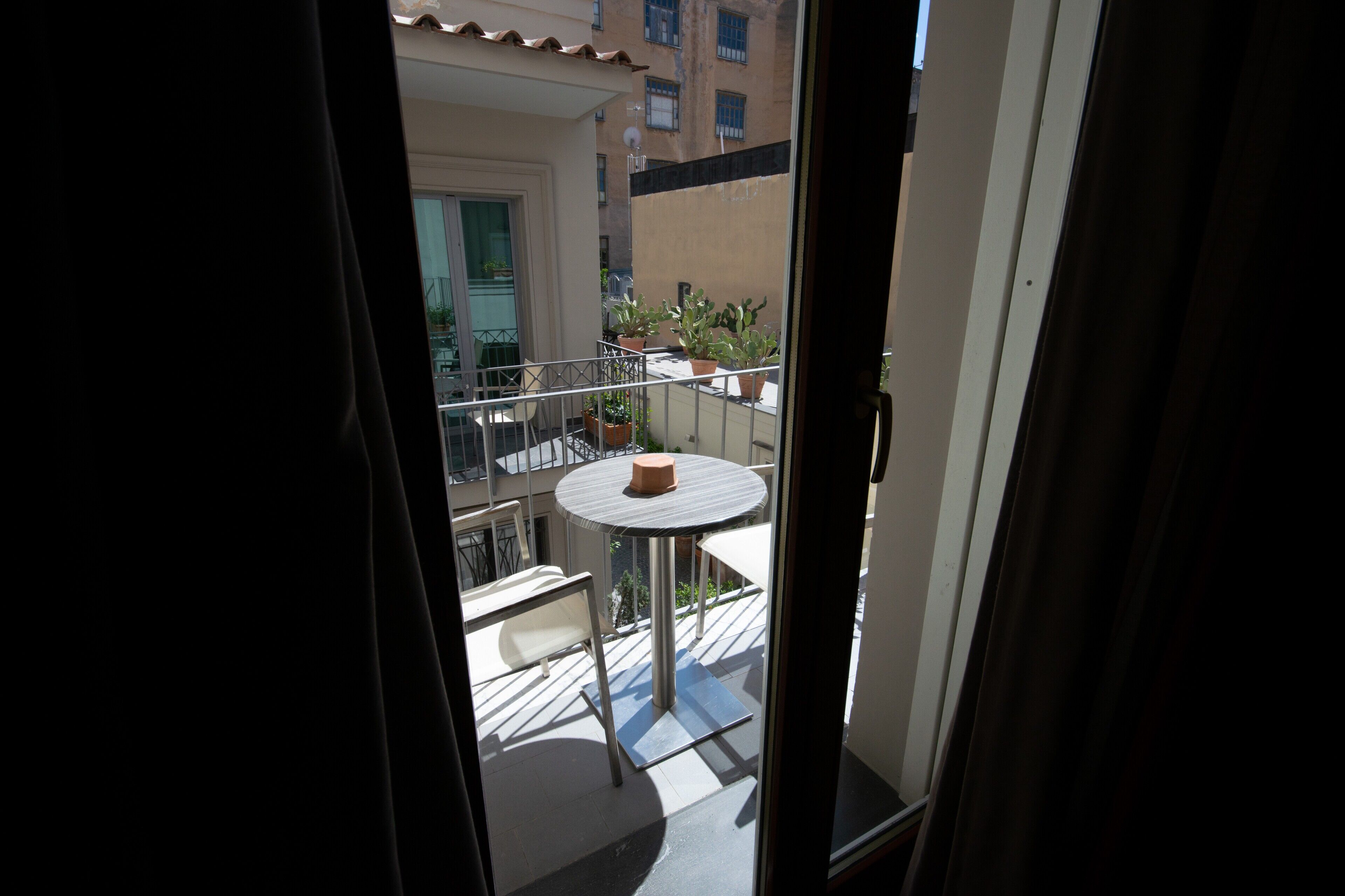 A balcony with a round table and potted plants.