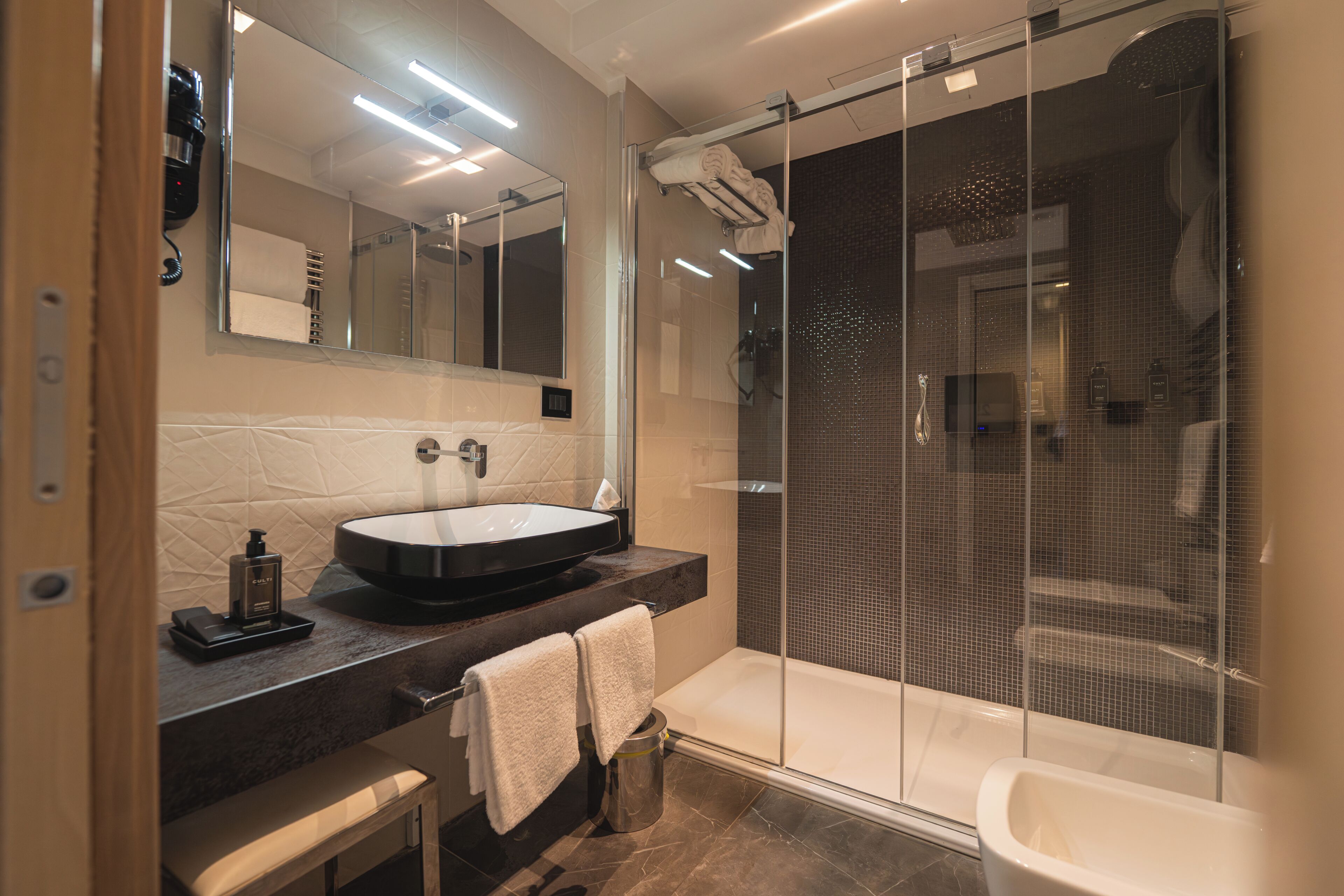 A modern bathroom with a large mirror, a sink, a shower enclosure, and a bathtub.