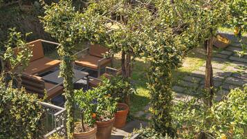 Una terraza con mobiliario exterior, rodeada de follaje y árboles.