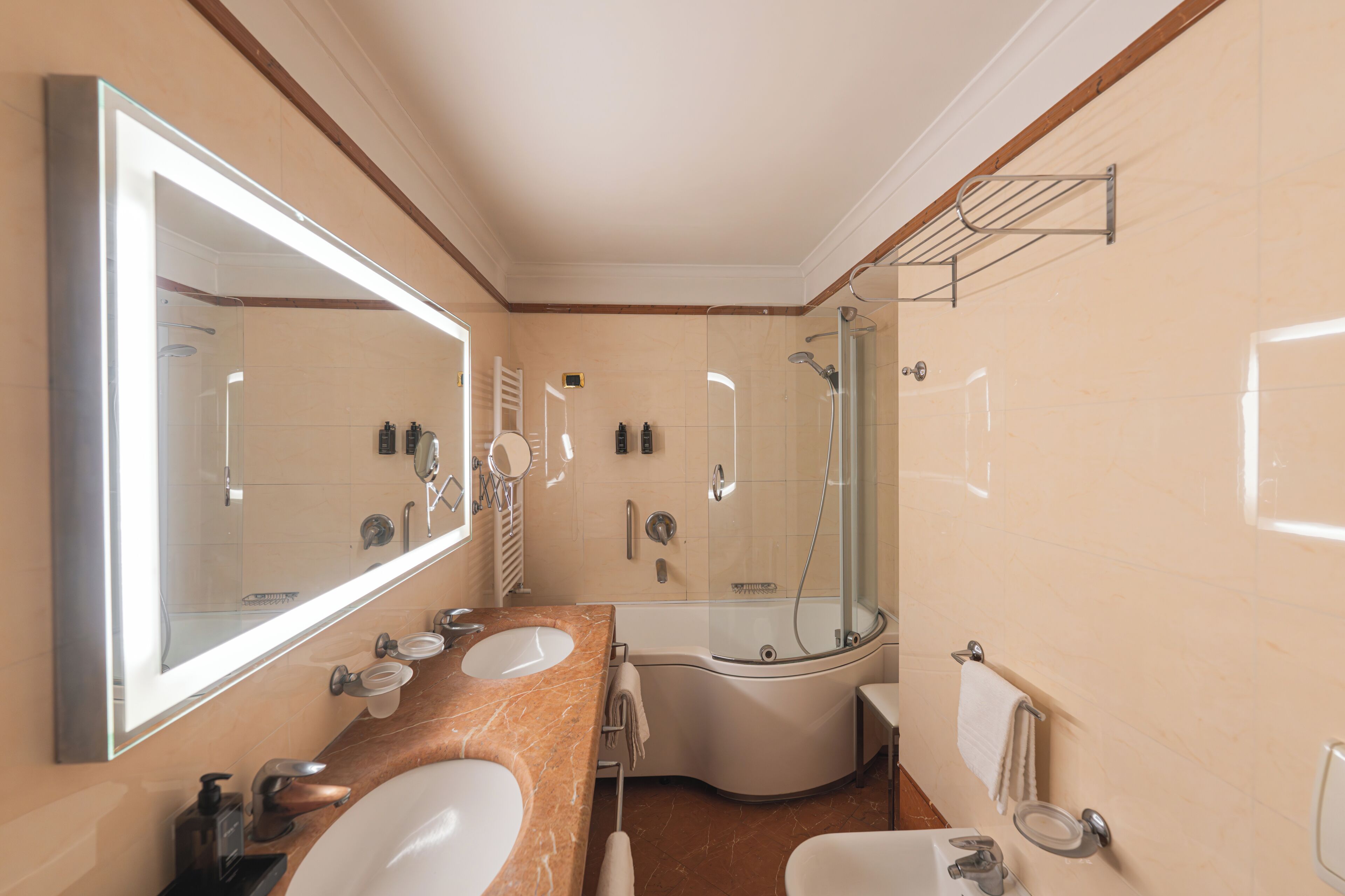 Ein Badezimmer mit großem Spiegel, zwei Waschbecken, einer Dusche und einer Toilette.