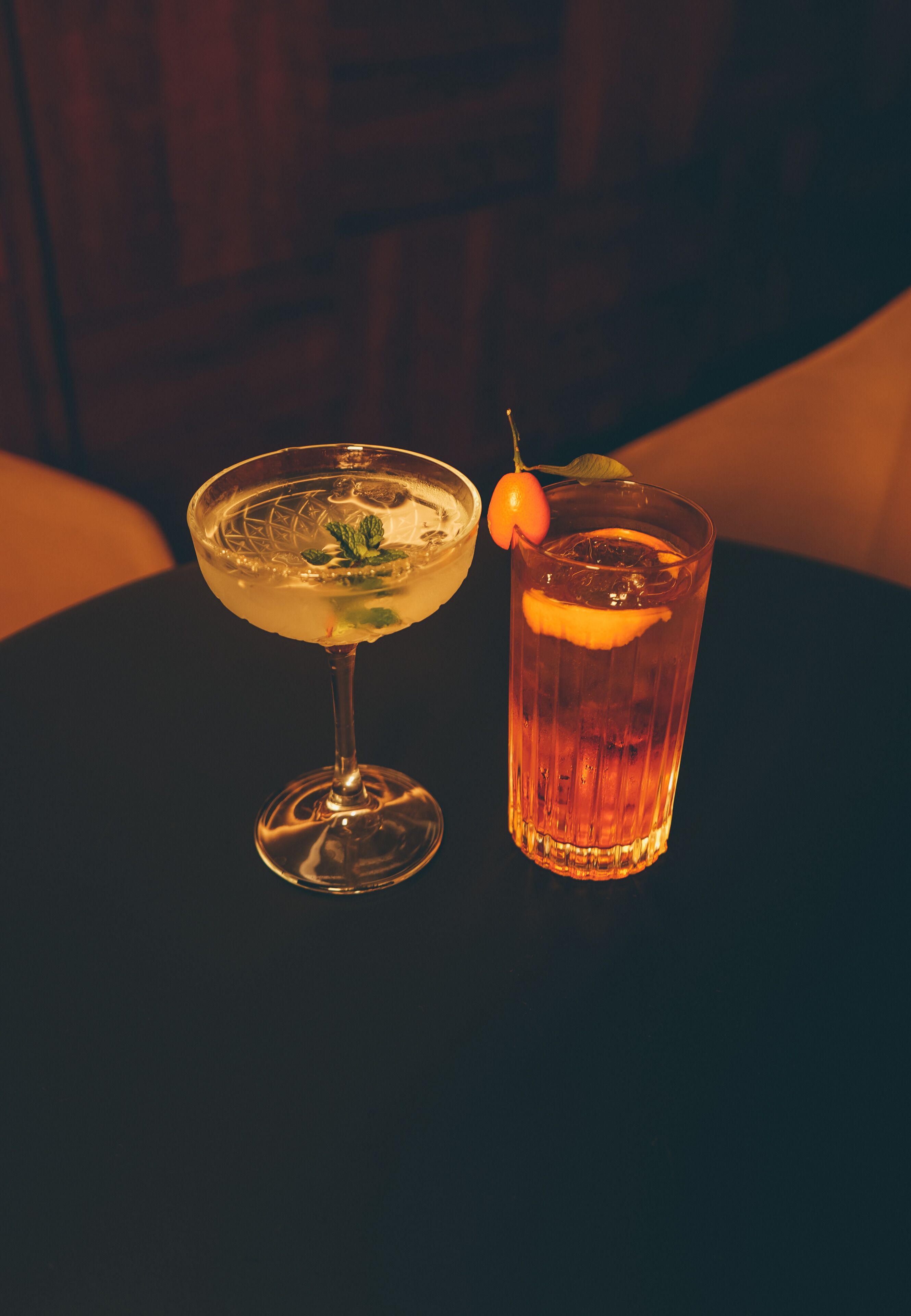 Two drinks on a table, one in a glass and one in a glass with a stem.