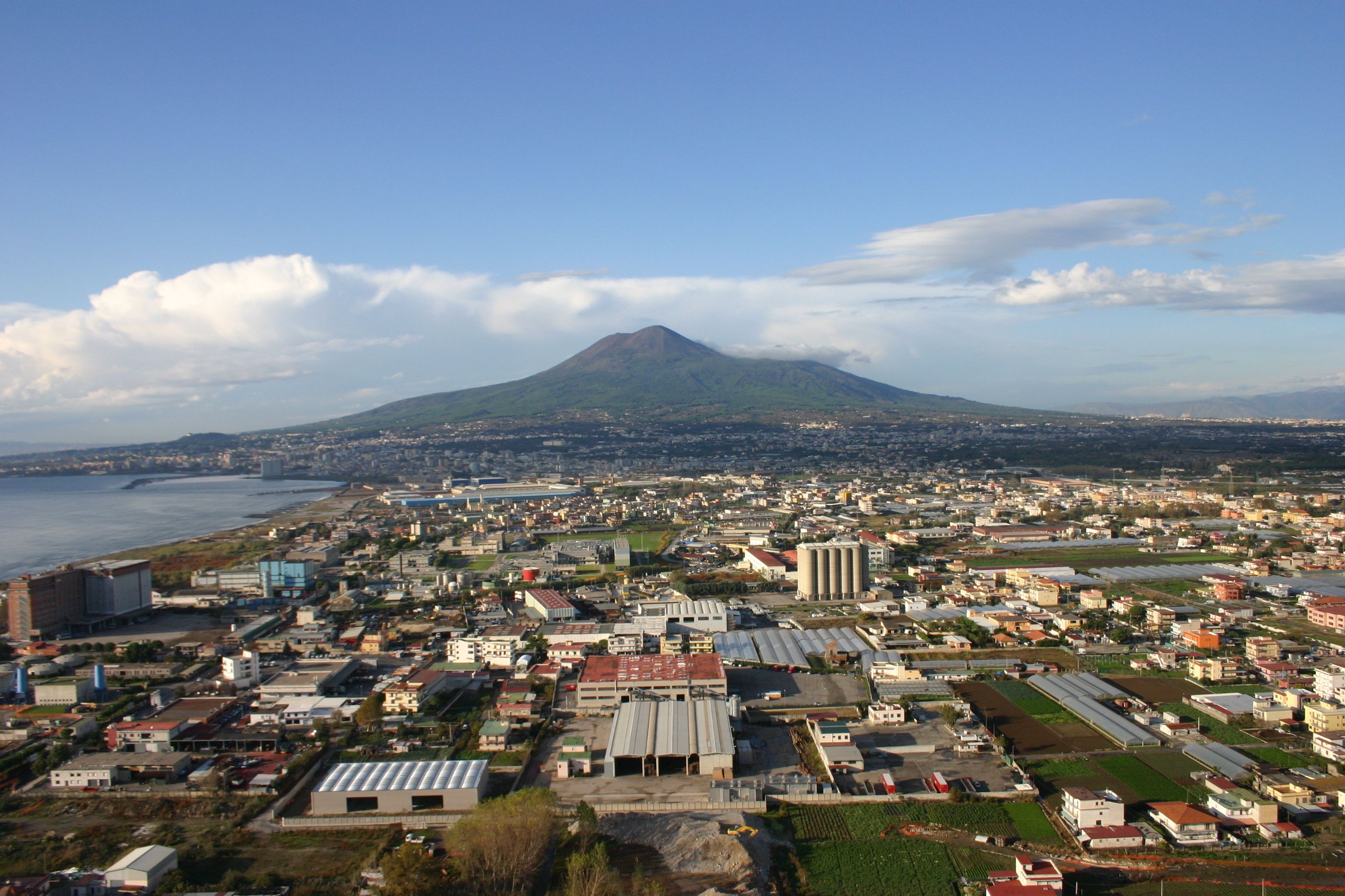 Une vue urbaine avec un volcan imposant en arrière-plan, entouré de bâtiments résidentiels et commerciaux.