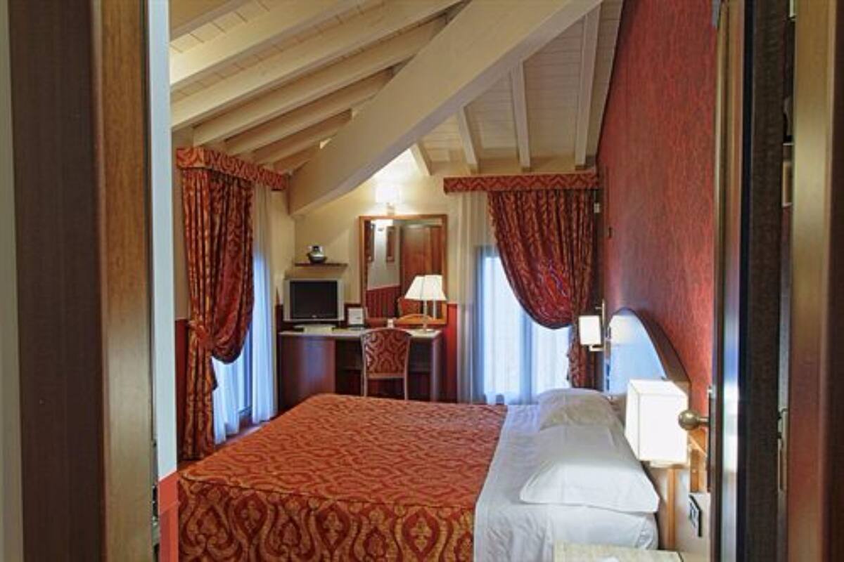 Una habitación de hotel con una cama grande, un escritorio con una computadora y una silla.