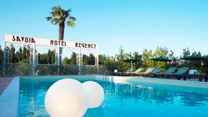 A swimming pool with a sign reading "SAVOIA HOTEL REGENCY" and lounge chairs along the poolside. - Savoia Hotel Country House (Bologna)