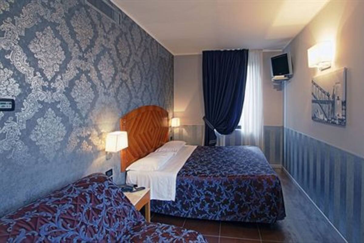 Habitación de hotel con dos camas, televisión y ventana con cortinas.