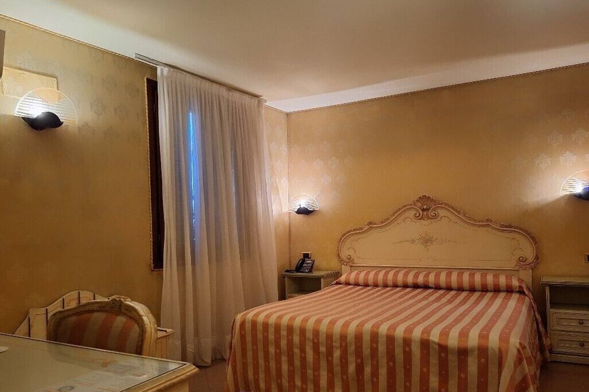 Et hotelværelse med seng, skrivebord og stol.