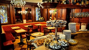 Een restaurant met een rode zithoek met banken, meerdere tafels en een buffet met diverse gerechten.