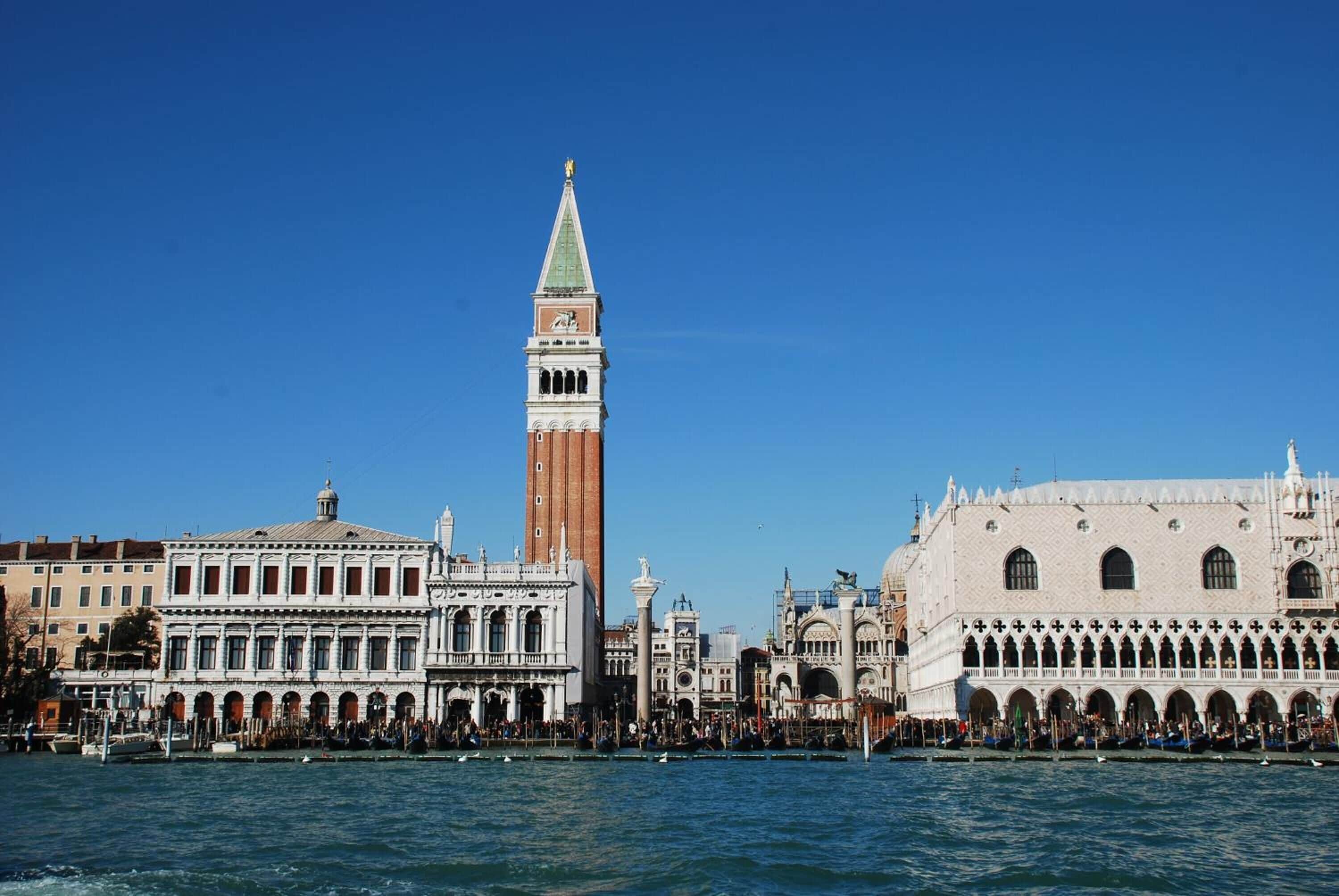A historic building with a prominent clock tower and a series of arches along the waterfront.