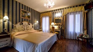 Hotelkamer met een groot bed, een bureau, een stoel, een spiegel en een kroonluchter.