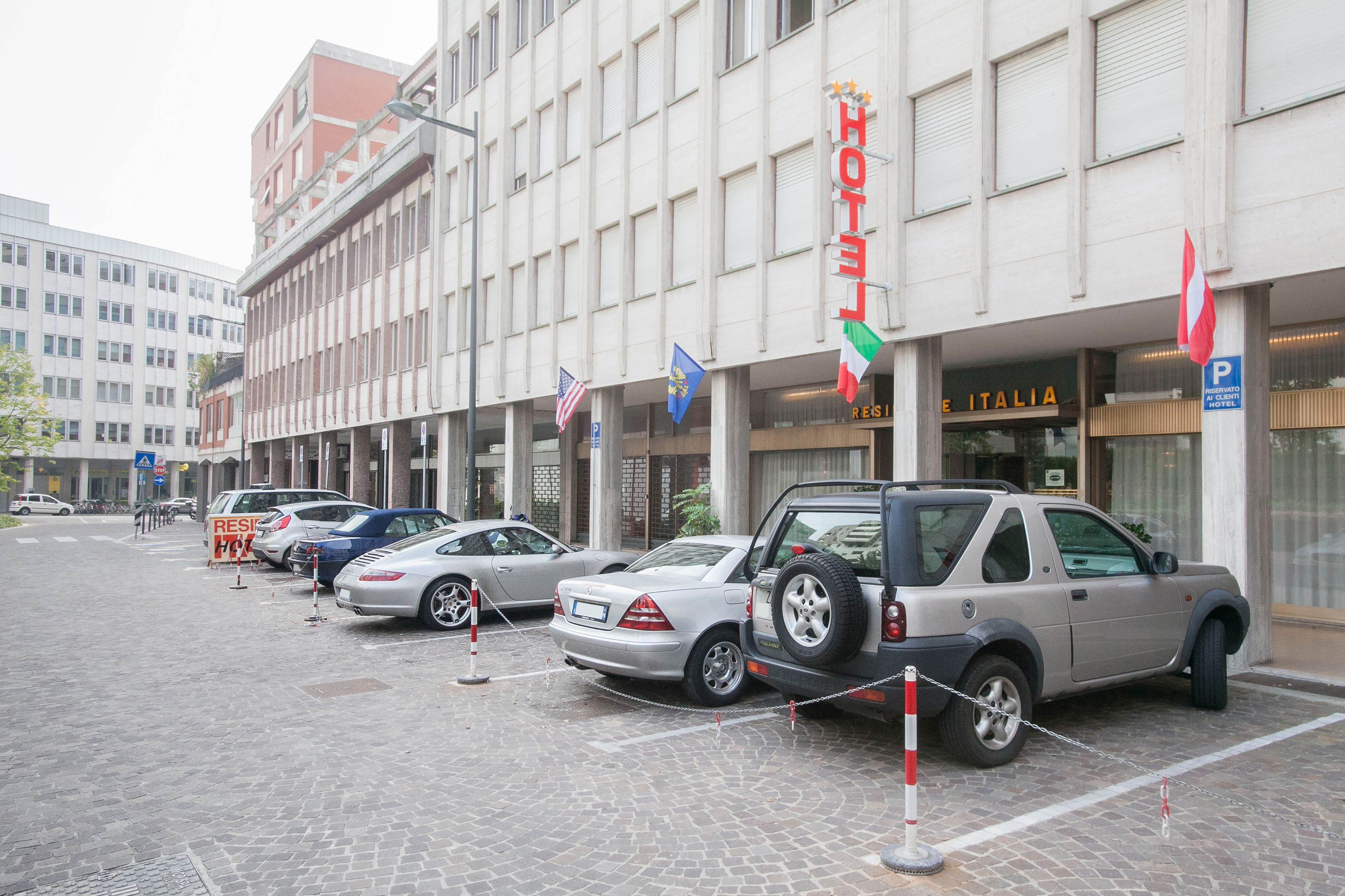 A hotel with a sign reading "HOTEL ITALIA" and a parking sign indicating a parking area.