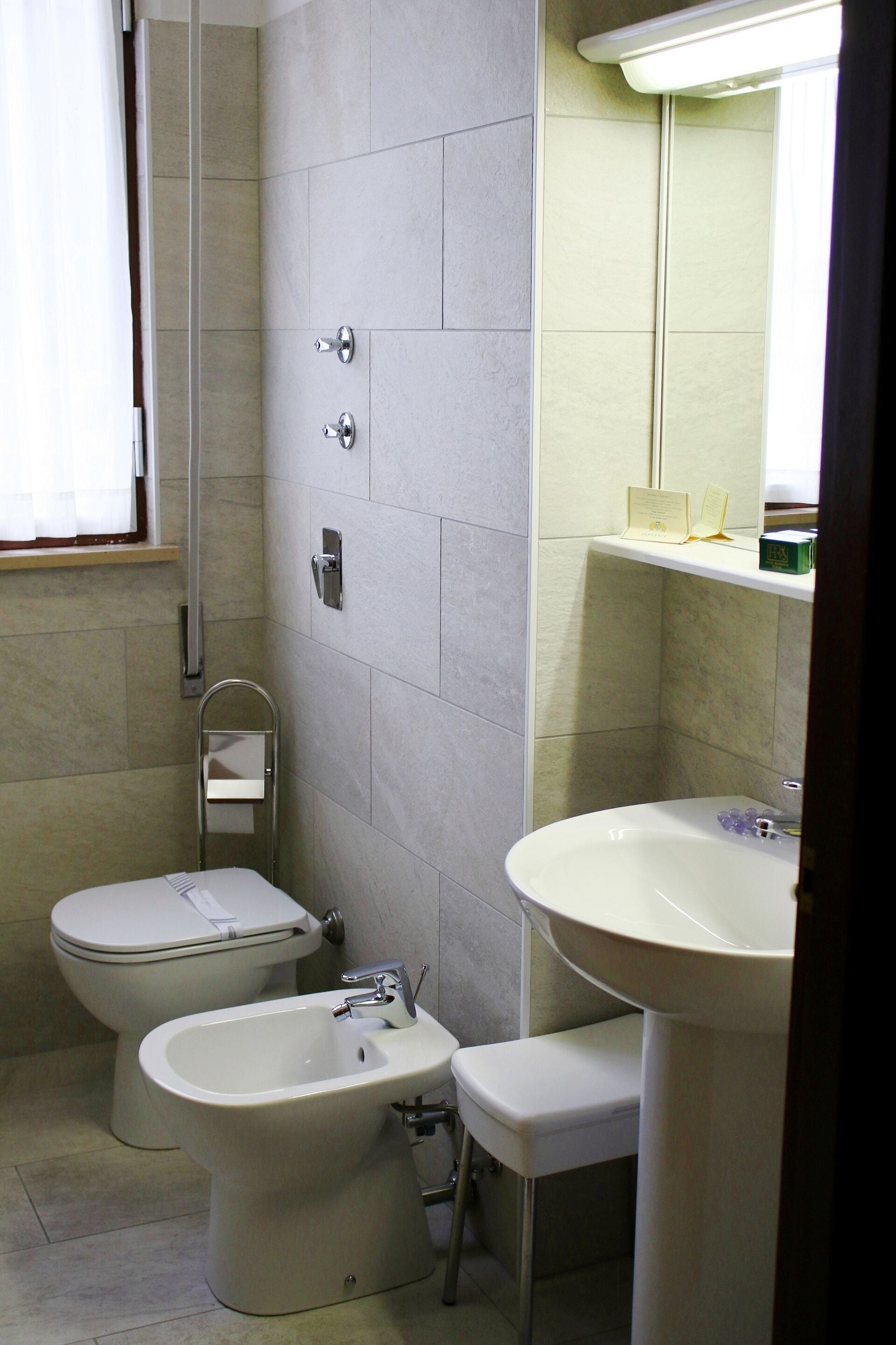 Un baño con inodoro, bidé, lavabo y un espejo sobre el lavabo.