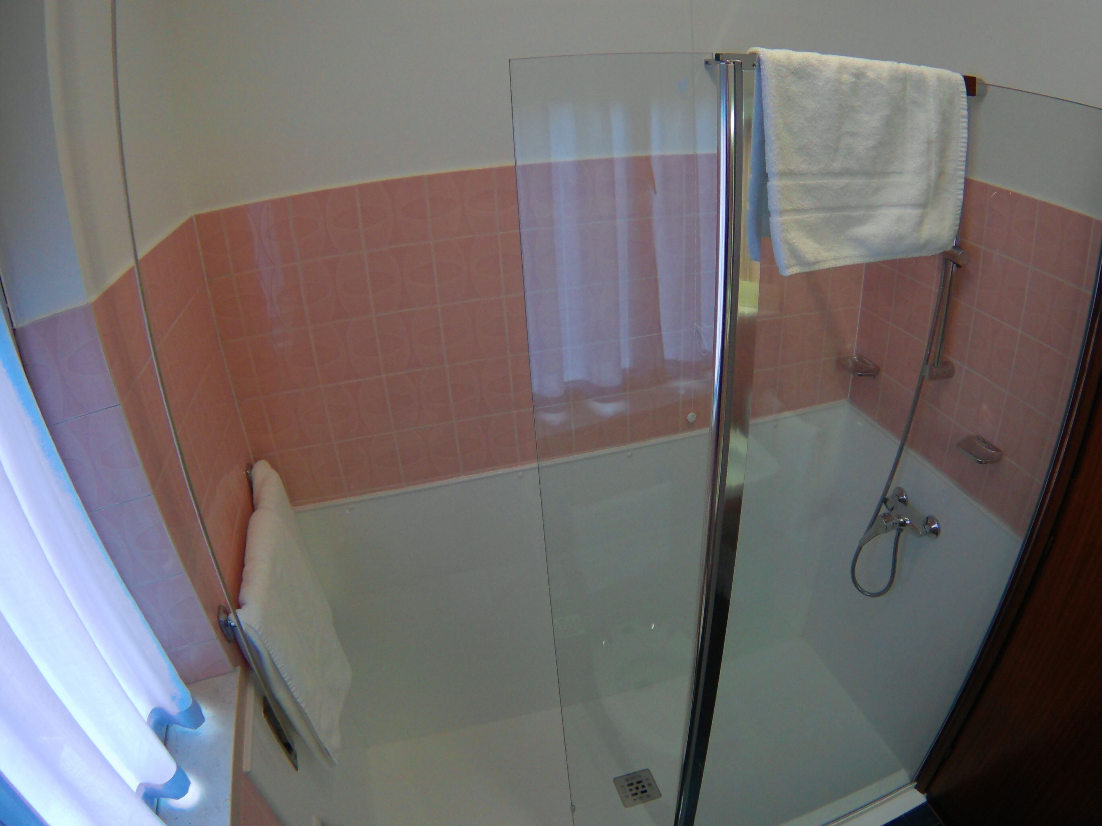 Eine Dusche mit Glastrennwand und ein weißes Handtuch, das an der Tür hängt.