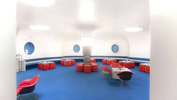 A room with a blue carpet, red and white furniture, and circular windows.