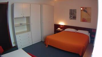A bedroom with a bed, a wardrobe, a desk, and a nightstand.